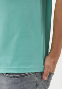 T-shirt turchese a maniche corte in misto cotone, con collo a girocollo a coste e piccolo logo sull'orlo. Tessuto morbido, vestibilità casual.