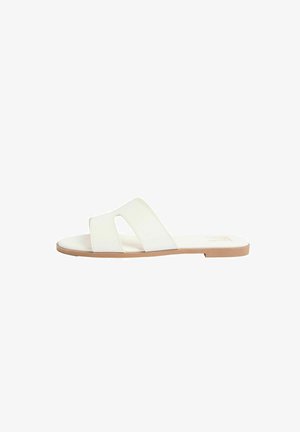 White flat slide sandal with wide cut-out strap and tan sole, designed for casual wear.