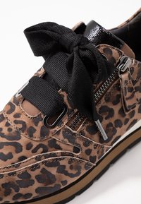 Zamszowy sneaker w panterkę z czarnymi kokardkowymi sznurowadłami, bocznym zamkiem błyskawicznym i czarnymi lakierowanymi akcentami. Posiada solidną gumową podeszwę.