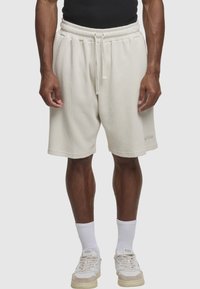 Lysebeige bomuldsblandede shorts med en struktureret finish, snøre i taljen og logodetalje på kanten. Bruges med hvide sokker og sneakers.