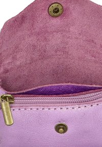 Interior de bolsa de cuero rosa con textura de ante, con un cierre a presión de latón y un bolsillo con cremallera forrado en tela morada.