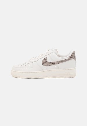Sapatos Nike Air Force 1 em couro branco com um padrão cinza texturizado no calcanhar e no swoosh, apresentando um colarinho acolchoado e uma sola de borracha.