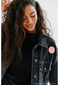 Czarna dżinsowa kurtka z srebrnymi guzikami, noszona na czarnej koszuli. Posiada okrągły pomarańczowy przypinek na klapie z napisem "Jak leci? Przyjaciele."