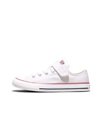 White low-top canvas sneaker with Velcro strap, metal eyelets, and red and blue stripes on the rubber sole.