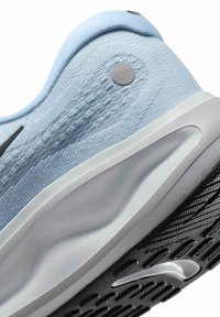 Zapatilla deportiva azul claro con parte superior de tela texturizada, entresuela blanca y suela de goma con un patrón de tacos negros y detalle del logo.