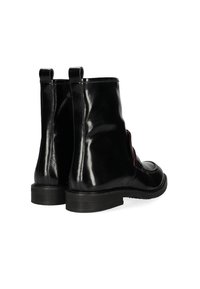 Bottines à talon noires en cuir poli avec une finition brillante, double tirette, bout rond et semelle en caoutchouc texturée. Inclut des accents sur les côtés.