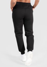 Svarta joggingbyxor i mjukt tyg, med en ribbad midja och smalnade mudd. Designen är elegant utan synliga mönster eller detaljer.