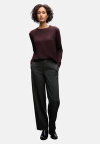 Pull bordeaux avec un col côtelé, associé à un pantalon gris ajusté et des bottines noires. Tissu texturé et coupe décontractée.