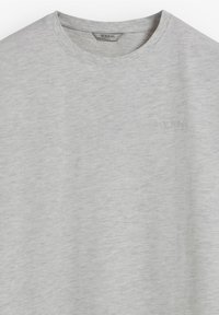 Camiseta gris de algodón con cuello redondo, con textura sutil y un logotipo en relieve de "SCALPERS" en el frontal, sin estampados.