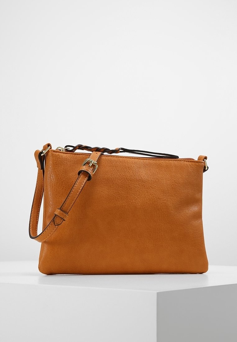 Väri: ruskea, nahkainen crossbody-laukku, jossa on karkea pinta, säädettävä olkahihna ja vetoketjukiinnitys. Yksinkertainen suorakulmainen muoto, jossa on vähäisesti kiinnityksiä.