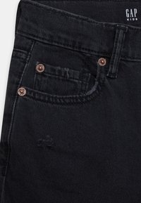 Svarta denimjeans med en standard femficksdesign, kopparfärgade nitar och subtila sömnadsdetaljer. Tyget har en mjuk textur.