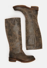 Paire de bottes hautes en cuir marron usé, avec des talons bas en bois empilés, des coutures latérales et des bouts arrondis, vues de côté et de face.