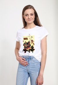 Weißes Baumwoll-T-Shirt mit buntem "Marvel Zombies"-Grafikdruck, rundem Ausschnitt und umgeschlagenen kurzen Ärmeln. Getragen mit hellblauen Jeans.