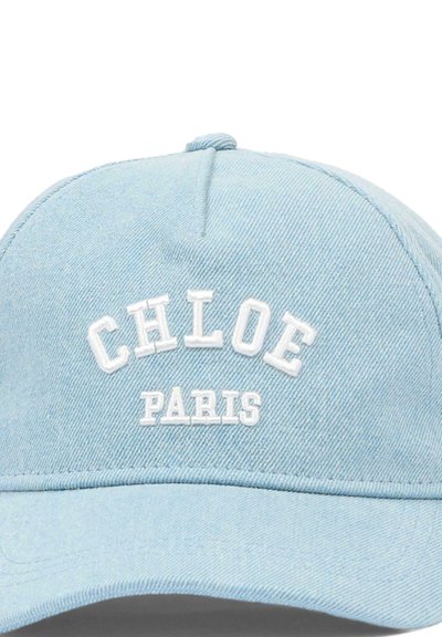 Jasnoniebieska czapka bejsbolowa z denimu z białym haftowanym napisem "CHLOE" nad "PARIS", umieszczonym na środku przedniej części czapki.