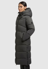 Tumehall puffer jope, millel on kapuuts, kujundatud tikandid, lukuga taskud ja logo aktsent varrukal.