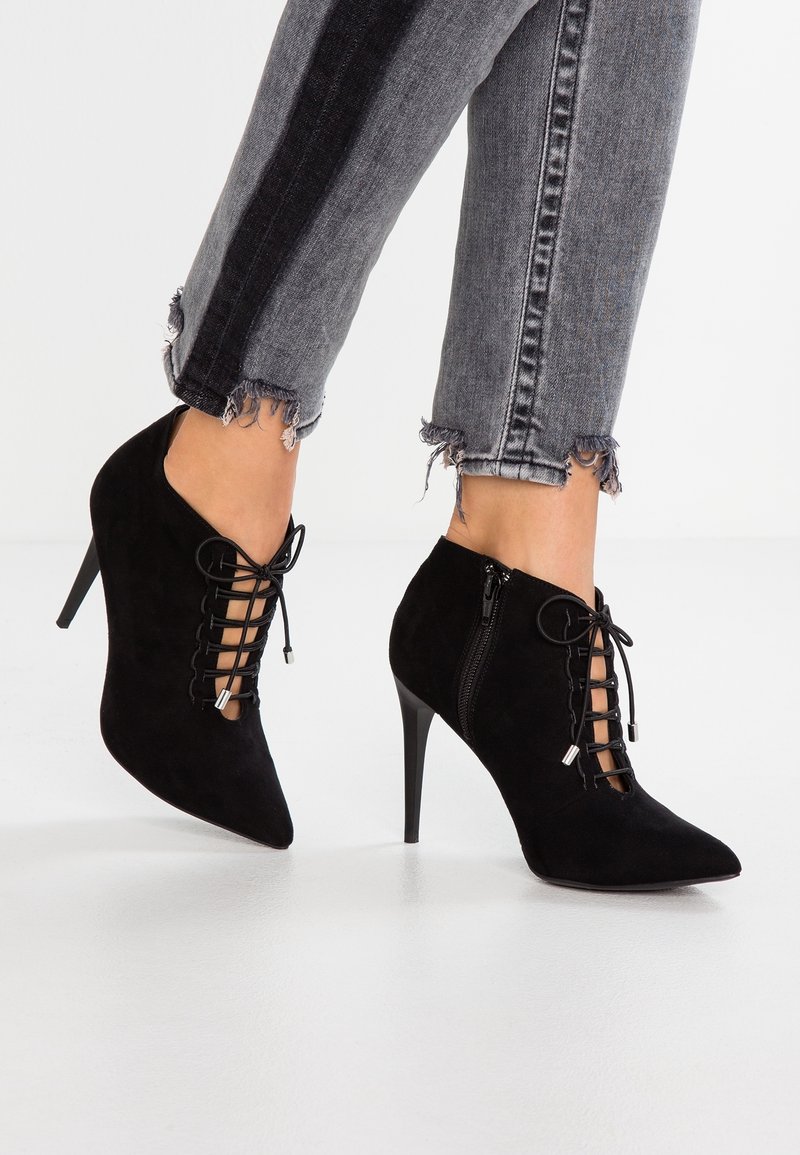 Bottines en daim noir à bouts pointus, lacets à l'avant et fermetures éclair latérales. Design à talons avec une texture lisse et des accents minimaux.