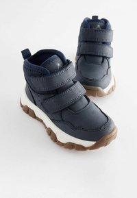 Blå hög-top sneakers med två kardborreband, en texturerad överdel och en kontrasterande gummisula. Har en vadderad krage för komfort.