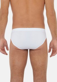 Weiße Baumwollslips mit glatter Textur, elastischem Bund und klassischem Schnitt, von hinten betrachtet, die minimalistische Gestaltung zeigend.