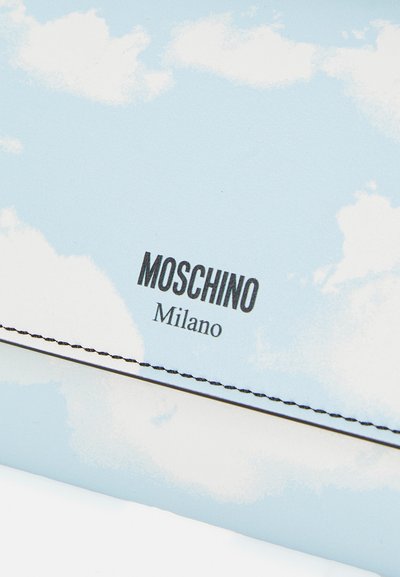 Moschino piniginė su šviesiai mėlynu fonu, debesų raštais, juodu prekės ženklu ir kontrastingais juodais siūlėmis aplink kraštus.