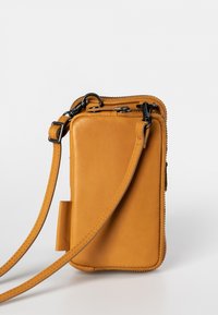 Yellow leather crossbody bag with a zipper closure, featuring an adjustable strap and smooth texture, designed for practical use.