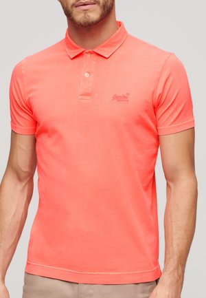 Polo di un brillante colore corallo con una morbida texture in cotone, colletto classico e un logo ricamato discreto sul petto. Maniche corte.