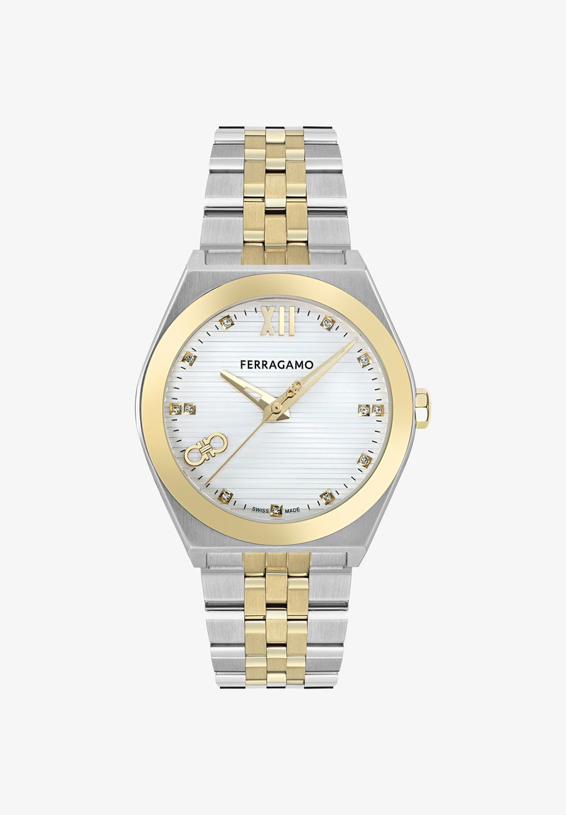 Hõbedane ja kuldne kell, millel on oktagonaalne korpus, valge tekstureeritud nägu, kuldsed käed, indeksmarkeerijad ja kahetooniline link-rihm.