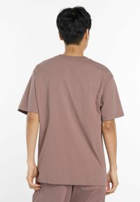 Lyhythihainen, rento T-paita hillityssä mauven sävyssä, valmistettu pehmeästä kankaasta, jonka pyöreä pääntie ei sisällä erottuvia kuvioita tai koristeita.