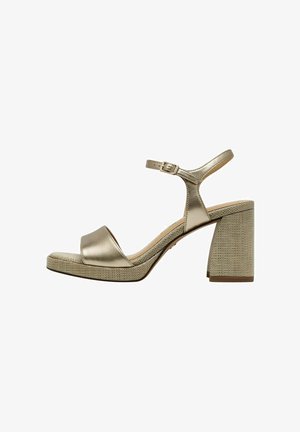 Sandale à talons hauts dorée métallisée avec un bout ouvert, une bride de cheville et un talon bloc texturé doré. Dispose d'un cuir lisse et d'accents tissés.
