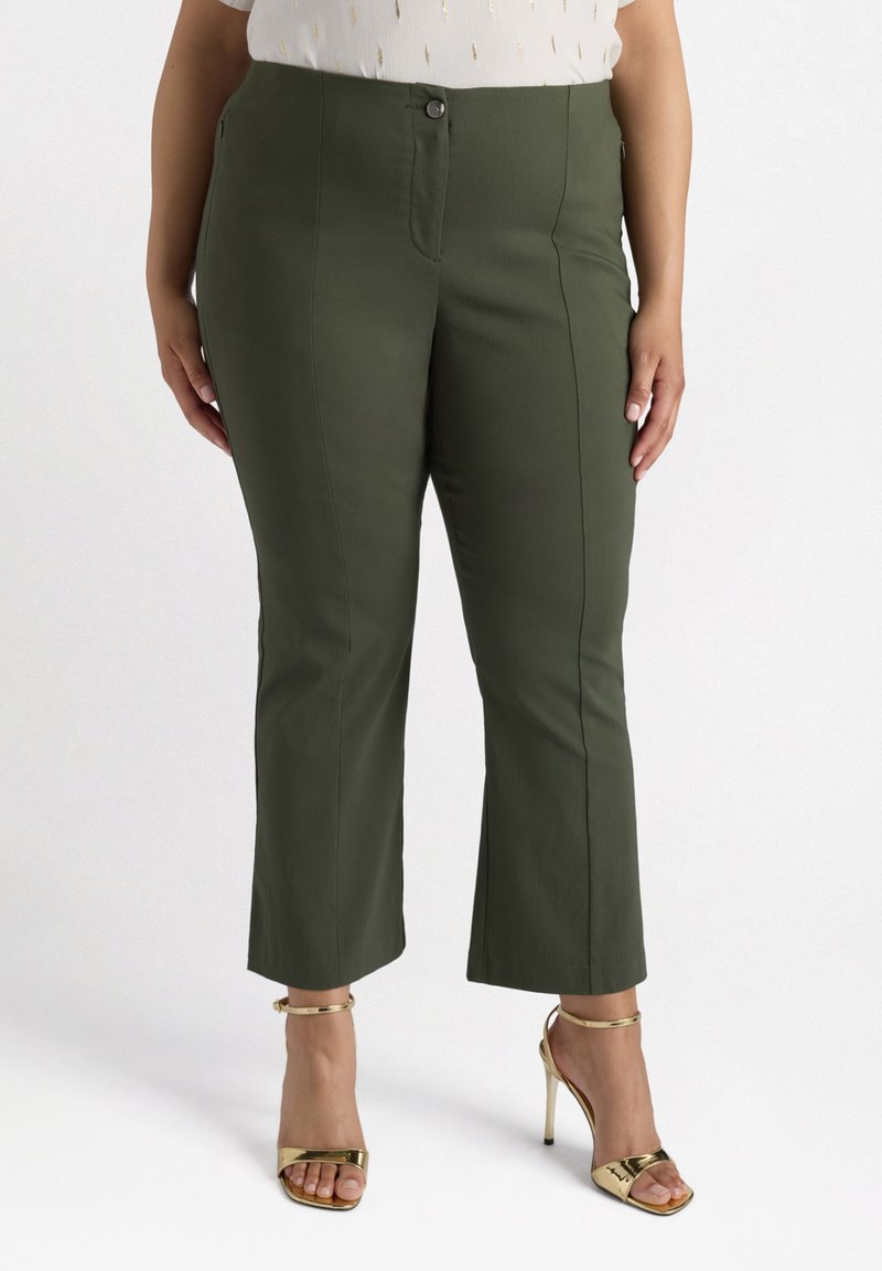 Olivově zelené kalhoty s přiléhavým střihem, předním zipem a knoflíkovým zapínáním, zúženými nohavicemi a bočními kapsami. Nosené s zlatými sandály na vysokém podpatku.