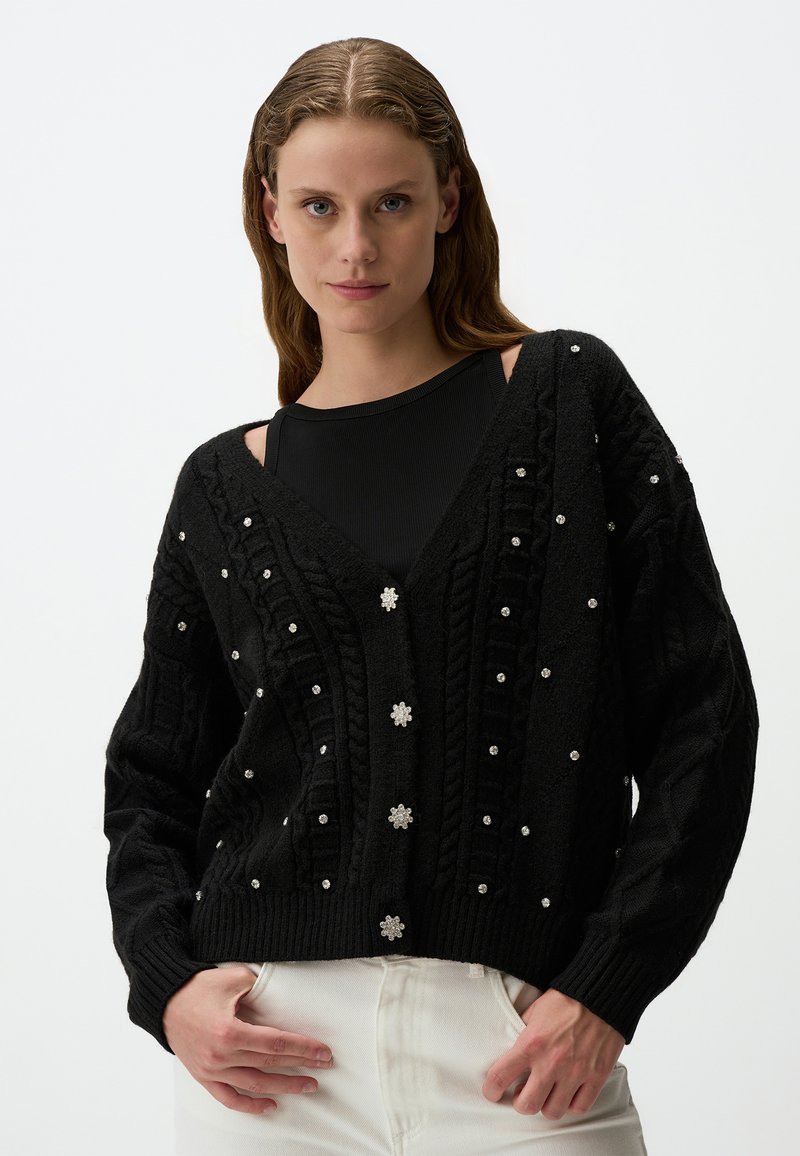 Zwarte gebreide cardigan met een V-hals, met een textuurpatroon en decoratieve parelaccenten, knoopsluiting en geribde manchetten.