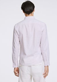 Camisa de manga larga de tejido ligero, con finas rayas verticales azules y rosas, puños con botones y un cuello clásico.