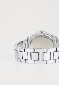 Silberner Edelstahl-Uhr mit einem Armbanddesign aus Gliedern, das glatte, polierte Oberflächen und ein rundes Gehäuse mit einer einfachen Krone aufweist.