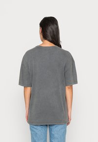 Grå oversized t-skjorte, korte ermer, rund halslinning, bomullsmateriale med myk tekstur, med en falmet finish og uornamentert design.