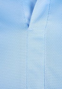 Tissu bleu clair présentant un motif texturé, avec un décolleté en V et des détails de couture subtils. Surface lisse, ton frais.