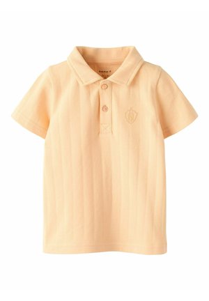 Koszulka polo w kolorze brzoskwiniowym z kołnierzykiem, krótkimi rękawami i zapięciem na trzy guziki. Posiada teksturowaną tkaninę oraz małe, haftowane logo na piersi.