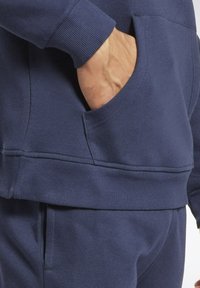 Mørkeblå sweatshirt med ribbede manchetter og kant, der har en sidelomme. Blød tekstur og afslappet silhuet. Komfortabel og afslappet design.