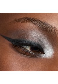 Nahaufnahme eines Auges mit silbernem Lidschatten, dramatischem schwarzem Eyeliner und definierten Wimpern. Die Haut hat einen glatten, dunkelbraunen Ton.