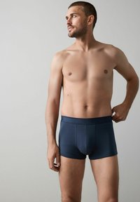 Mörkblå bomullsboxershorts med en slät textur, utrustade med en märkeselastisk midjerem och en tajt passform.