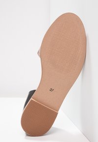 Sandal sula med beige texturerad botten, räfflad klack för grepp, och storleksnummer 37 stämplat nära fotvalvet.