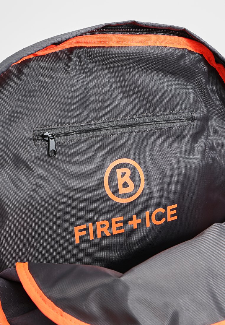 Wnętrze szarego plecaka z tkaniny, z pomarańczowymi wykończeniami, z zamykaną kieszenią i logo "FIRE+ICE" w kolorze pomarańczowym. Teksturowany materiał, praktyczny design.