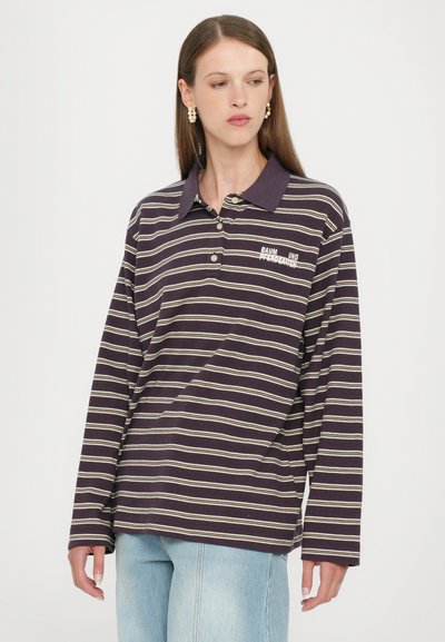 Polo de manga larga, color marino, con rayas blancas y beige, que presenta un cuello y un pequeño logotipo bordado en el pecho. Combinado con jeans claros.