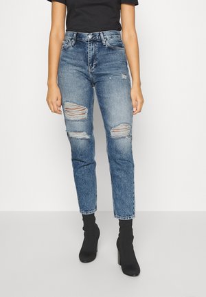 Jeans de tiro alto, de un azul claro desgastado con detalles de desgarro en las rodillas. Hechos de denim, con un corte recto y un desvanecimiento mínimo.
