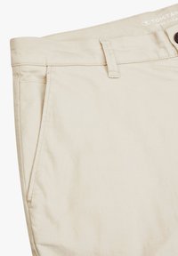Beige Baumwollhose mit flachem Vorderteil, seitlichen Taschen und Knopfverschluss. Verfügt über ein Logo-Tag und eine subtile Textur.
