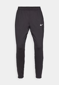 Sorte Nike treningsbukser med slim fit, elastisk linning og hvit logo på venstre lår. Glatt, stretchy stoff.