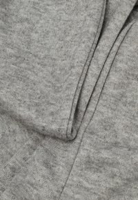 Tela gris con una textura suave y de punto, que presenta sutiles variaciones en el tono y un acabado liso, doblada cuidadosamente.