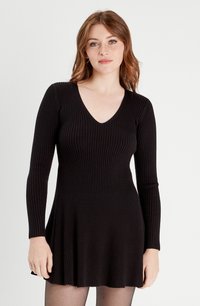 Czarna, prążkowana sukienka z dekoltem w serek, długim rękawem i rozszerzanym dołem. Wykonana z elastycznego materiału, z delikatnymi pionowymi liniami dla tekstury.