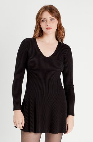 Czarna, prążkowana sukienka z dekoltem w serek, długim rękawem i rozszerzanym dołem. Wykonana z elastycznego materiału, z delikatnymi pionowymi liniami dla tekstury.