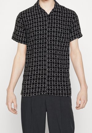 Schwarzes Kurzarmhemd mit geometrischem weißen Muster, Kragen-Design und Knopfverschluss. Der Stoff hat eine glatte Textur.