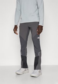 Szare spodnie outdoorowe w dopasowanym kroju, z ciemniejszymi panelami, wzmocnionymi dolnymi nogawkami oraz logo North Face na górnej części uda.