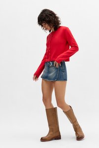 Rdeča pletena jakna s gumbi, denim mini krilo z pasom in rjave usnjene škornje do kolen s debelim peto.
